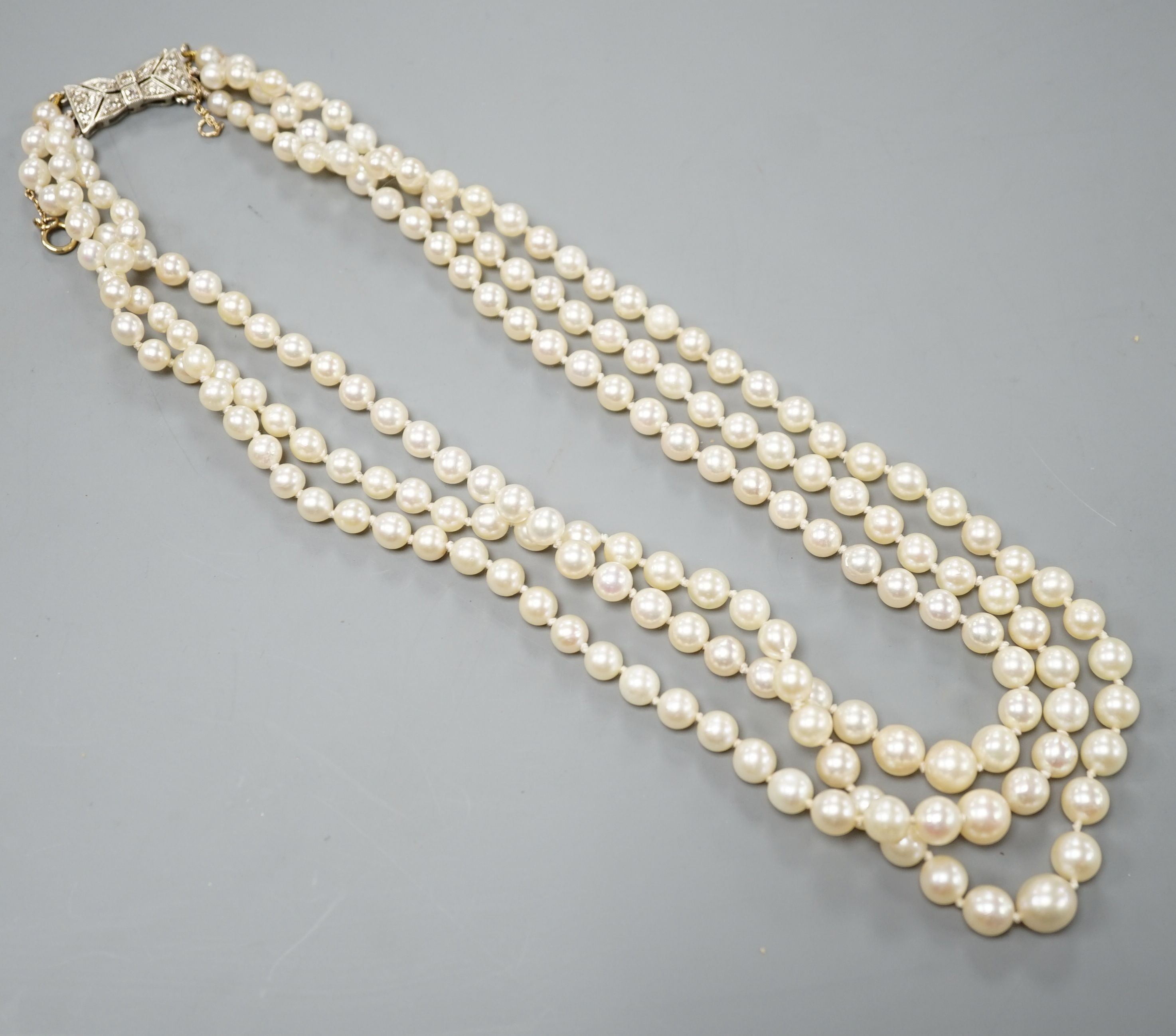 A modern triple strand graduated cultured pearl choker necklace, with diamond chip set white metal clasp, 38cm.